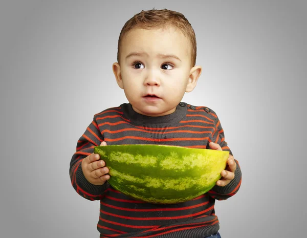 Porträtt av barn innehar en stor vattenmelon över grå bakgrund — Stockfoto