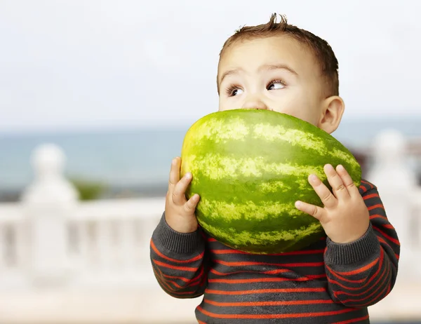 Retrato de um garoto bonito segurando melancia e chupando perto de t — Fotografia de Stock
