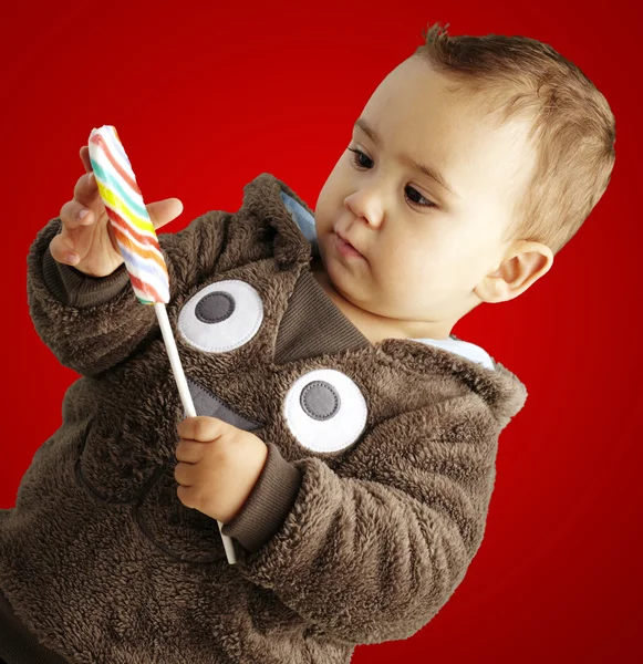 Porträt eines hübschen Kindes, das ein leckeres Bonbon hält und danach aussieht — Stockfoto