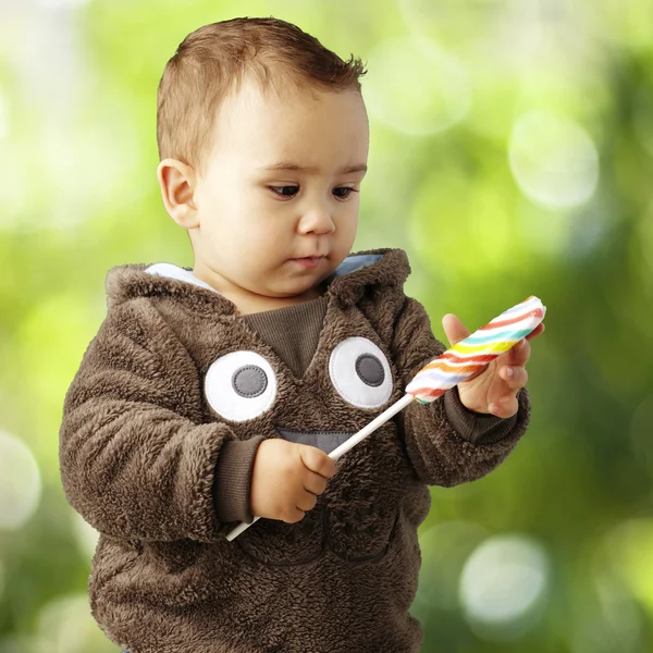 Портрет красивого ребенка, держащего и смотрящего на вкусные конфеты — стоковое фото