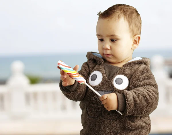 Портрет красивого ребенка, держащего в руках и смотрящего на вкусные конфеты — стоковое фото