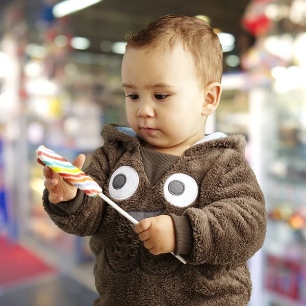 Portrét pěkný dítě drží a lahodné bonbony při pohledu — Stock fotografie
