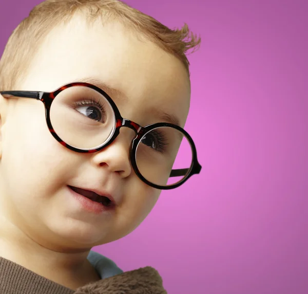 Retrato de criança doce vestindo óculos redondos sobre fundo rosa — Fotografia de Stock