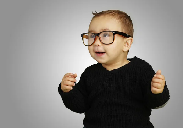 Retrato de un niño adorable con gafas y gestos sobre gris — Foto de Stock