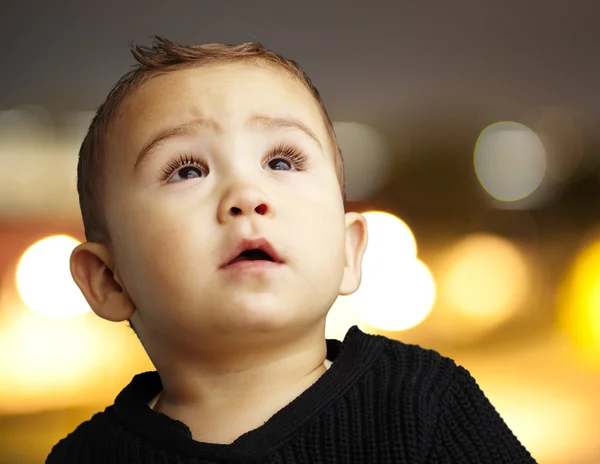 Portrait of a handsome kid looking up against at city by night — Stock Photo, Image