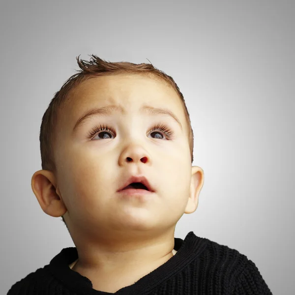 Portrait of a handsome kid looking up against a grey background, — Stock Photo, Image