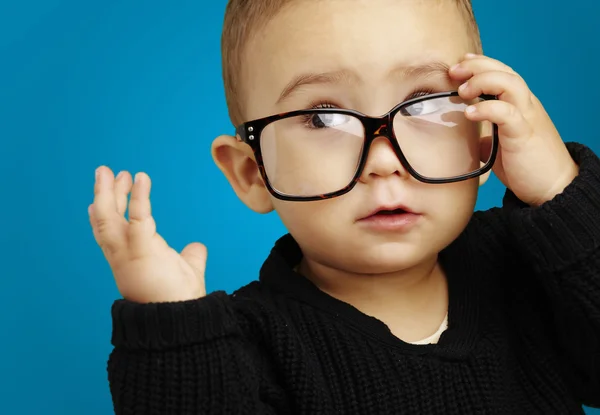 Portrait of serious kid wearing glasses and doing a gesture over — Stock Photo, Image