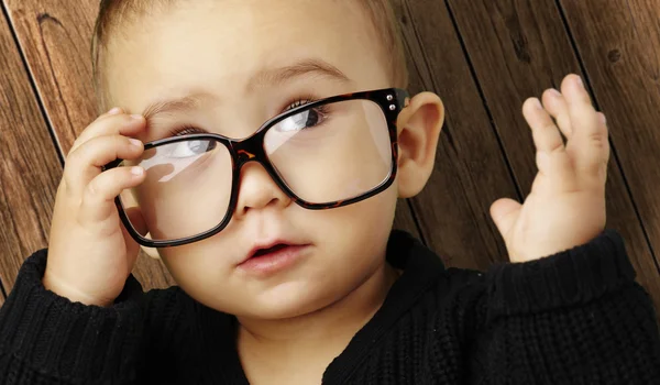 Retrato de niño con gafas y mirando hacia arriba contra una madera — Foto de Stock