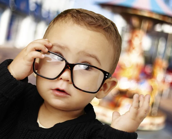 Porträt eines Kindes, das eine Brille trägt und gegen ein Karussell blickt — Stockfoto