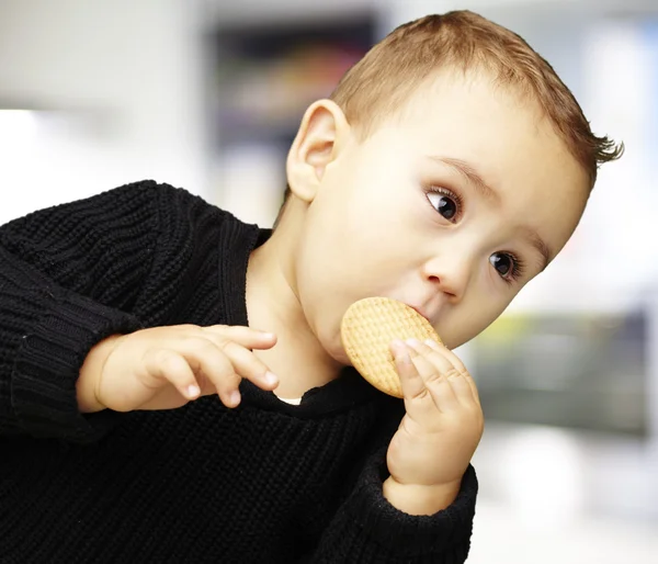 Porträt eines hübschen Kindes, das drinnen einen Keks isst — Stockfoto