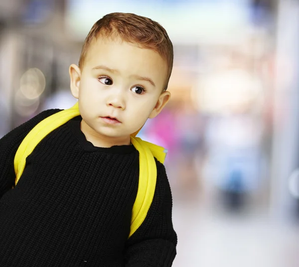 Retrato de niño adorable llevando mochila amarilla en una p lleno de gente — Foto de Stock