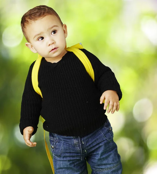 Portrait of adorable kid carrying yellow backpack against a natu — Stock Photo, Image