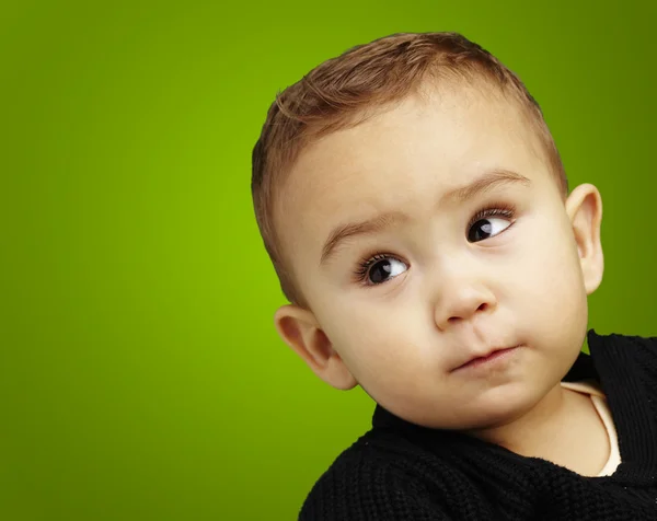 Портрет восхитительного младенца, смотрящего вверх на зеленом фоне — стоковое фото