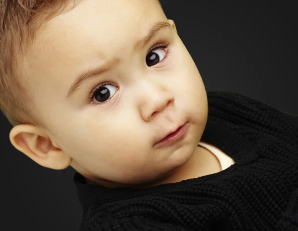 Retrato de niño serio mirando hacia adelante sobre fondo negro — Foto de Stock