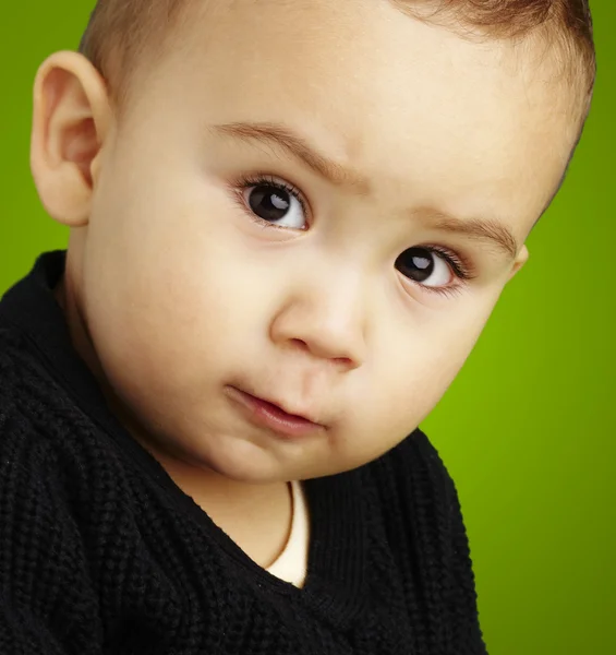 Porträt eines ernsthaften Kindes, das über den grünen Hintergrund blickt — Stockfoto