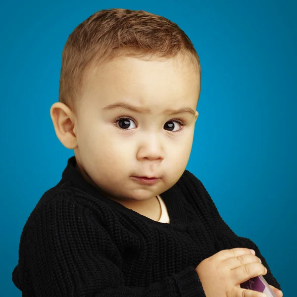 Porträt eines ernsthaften Kindes, das über blauen Hintergrund nach vorne blickt — Stockfoto