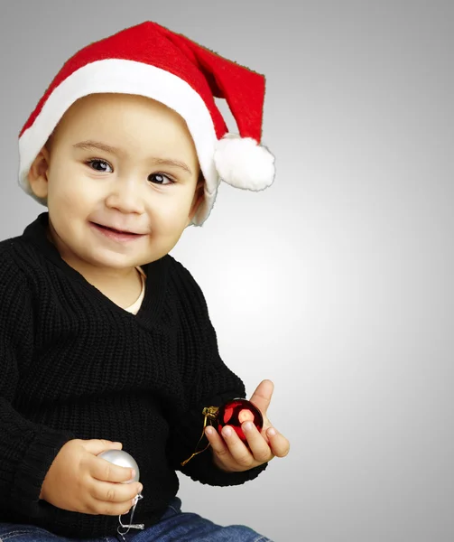Retrato de un niño feliz usando un gorro de Navidad sobre respaldo gris —  Fotos de Stock