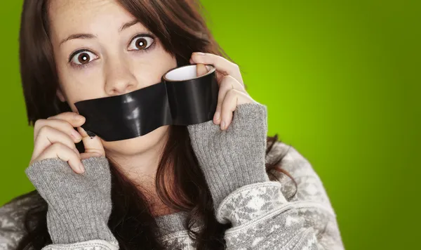 Portrait of scared girl being silenced by herself over green bac — Stock Photo, Image