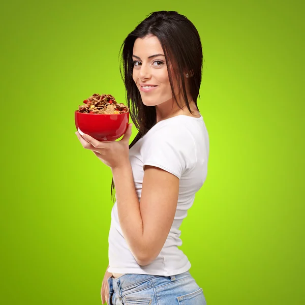 Portrait of young woman holding a cereal bowl over green backgro — Stock Photo, Image