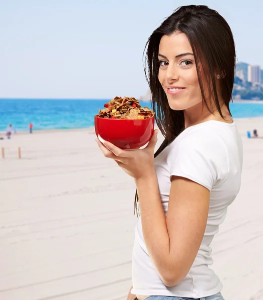 Здорові жінки, що тримає миску кукурудзяні пластівці на пляжі — стокове фото