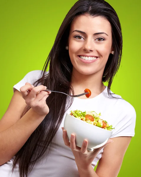 Портрет здоровой женщины, поедающей салат против зеленой спинки — стоковое фото