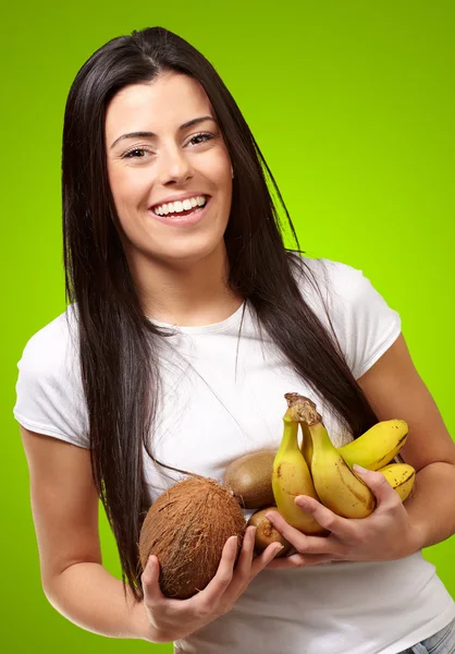 Portrét mladé ženy držící tropické ovoce proti zelené — Stock fotografie