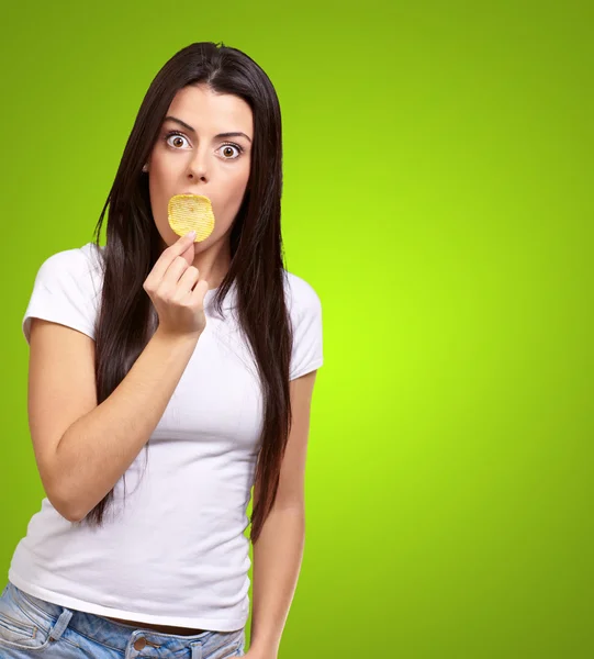 Ritratto di giovane donna con patatine in bocca sopra gr — Foto Stock