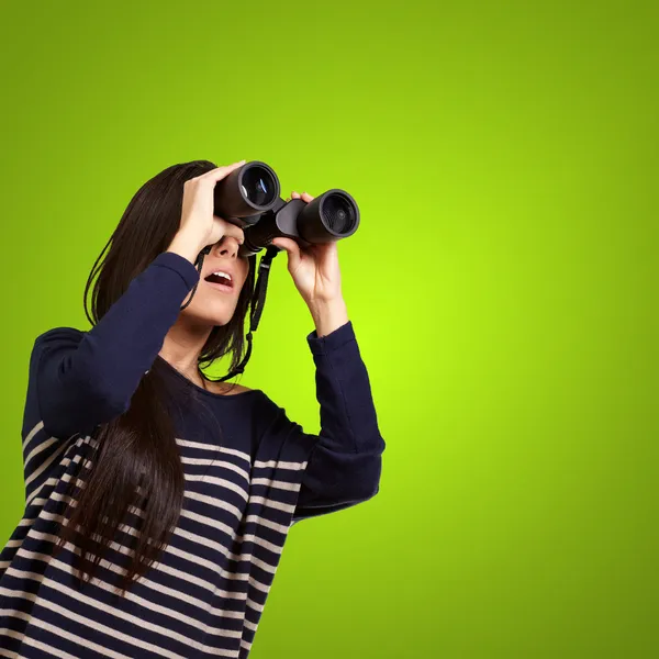 Retrato de una joven mirando a través de unos prismáticos sobre verde —  Fotos de Stock