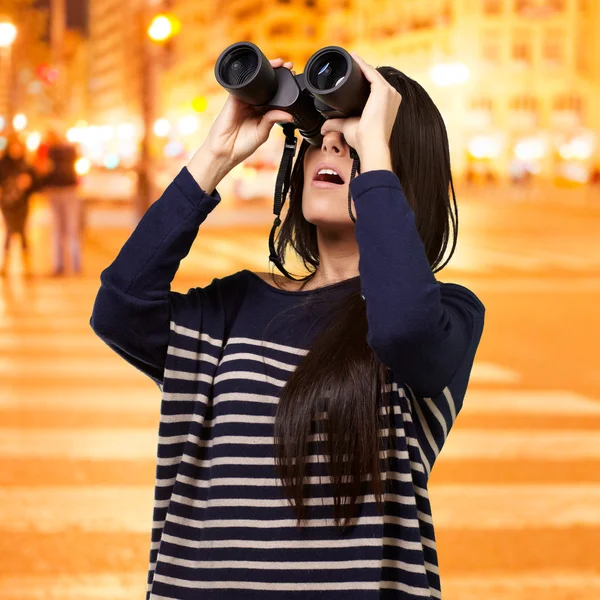 Retrato de una joven mirando a través de un prismáticos por la noche cit — Foto de Stock