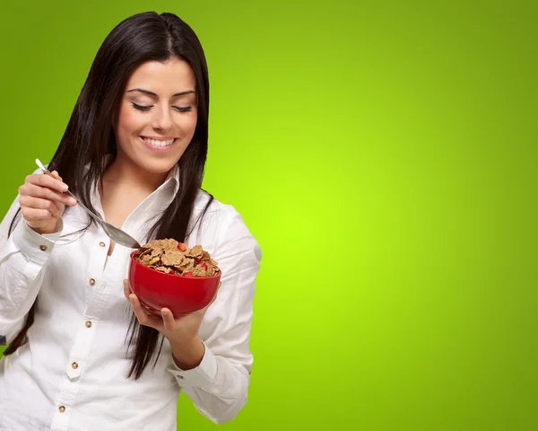 Portrait of healthy young woman eating cereals over green — Stock Photo, Image