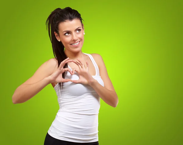 Portret van gezonde meisje gebaren hartsymbool over groen — Stockfoto