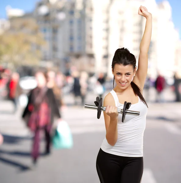 Портрет молодой женщины, занимающейся фитнесом с гирями на переполненной улице — стоковое фото