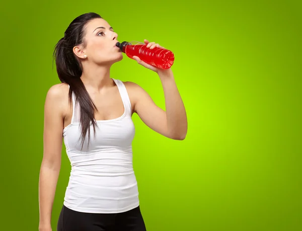 Ritratto di giovane donna sportiva che beve bevanda isotonica su gree — Foto Stock