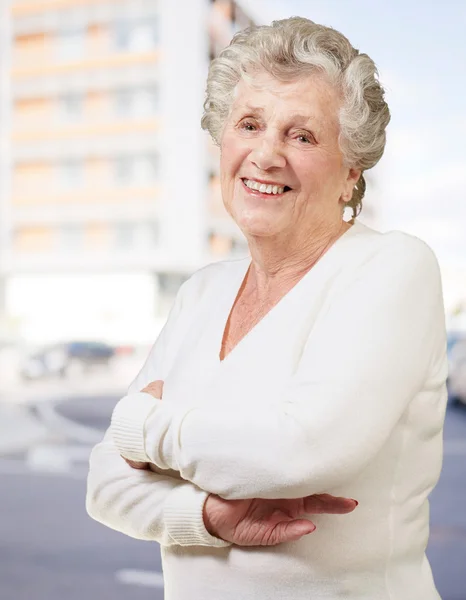 Portrait of senior woman smiling against a modern building — Stock Photo, Image