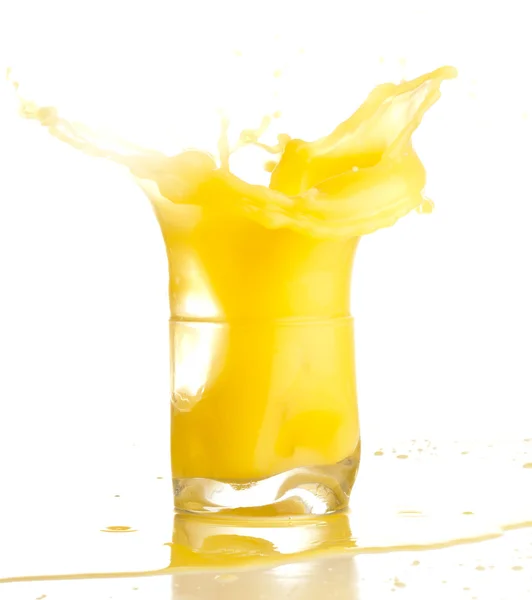 Χυμό πορτοκαλιού εκτίναξη προς ένα ποτήρι σε άσπρο φόντο — Φωτογραφία Αρχείου