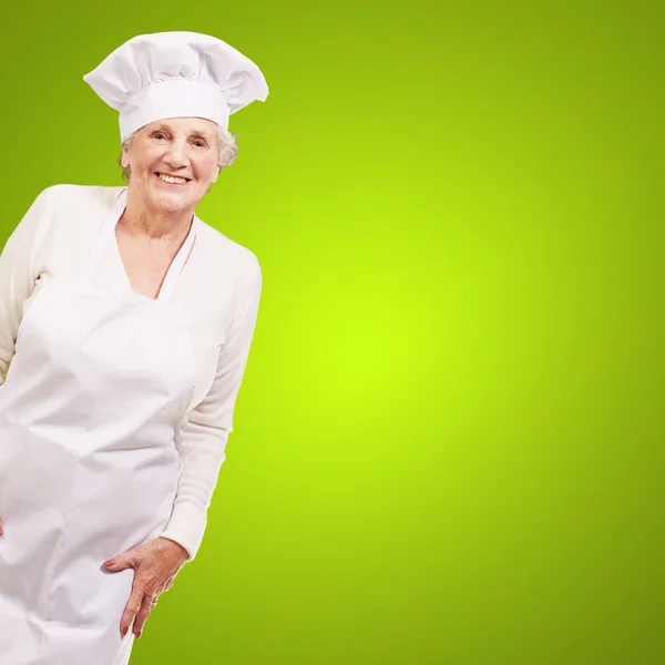 Portrait of cook senior woman smiling over green background Stock Image