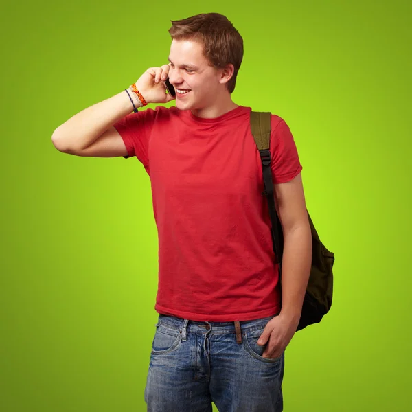 Portrait of young man talking on mobile over green background Stock Picture