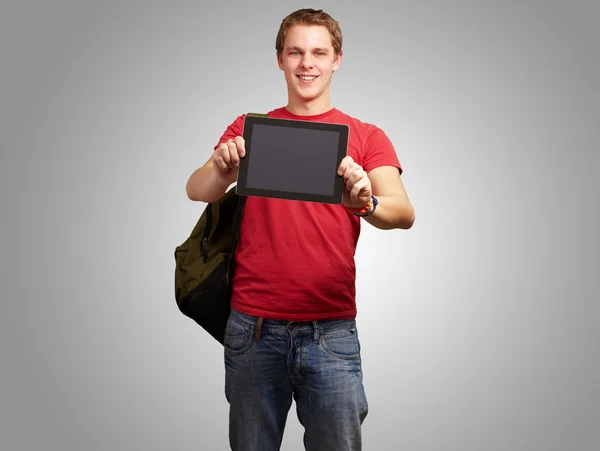 Retrato de un joven sosteniendo una tableta digital sobre fondo gris Fotos de stock libres de derechos