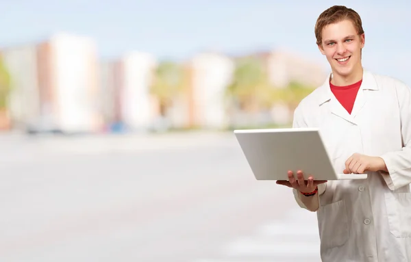 Porträtt av ung student hålla laptop mot en stadsbild Stockfoto