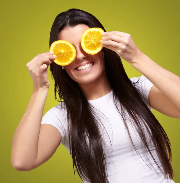 Portrait of young woman holding orange slices in front of her ey Stock Picture