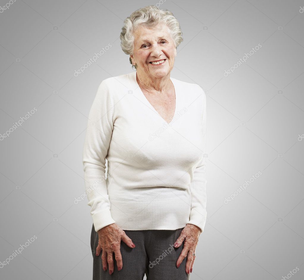 Pretty senior woman smiling against a grey background