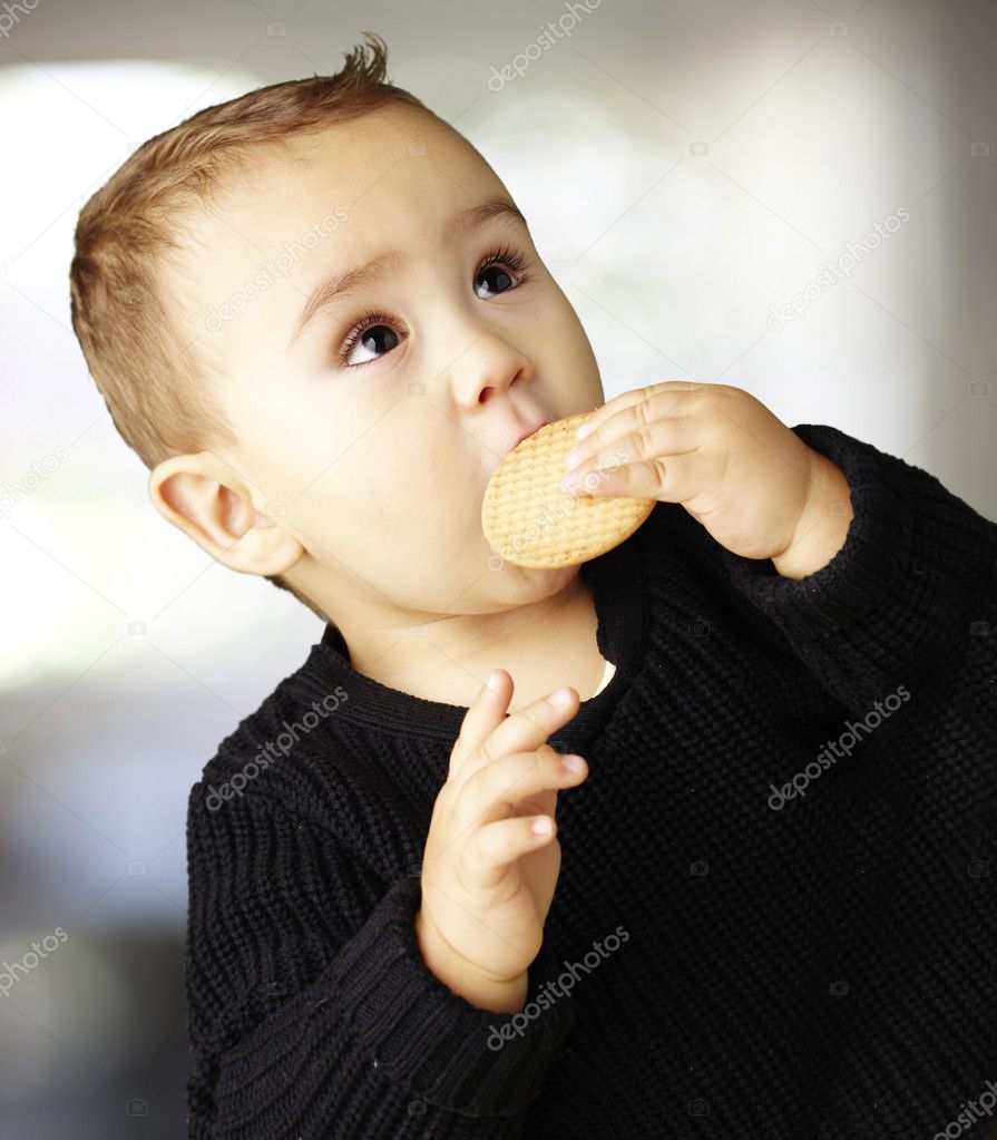 Portrait of handsome kid eating a biscuit indoor