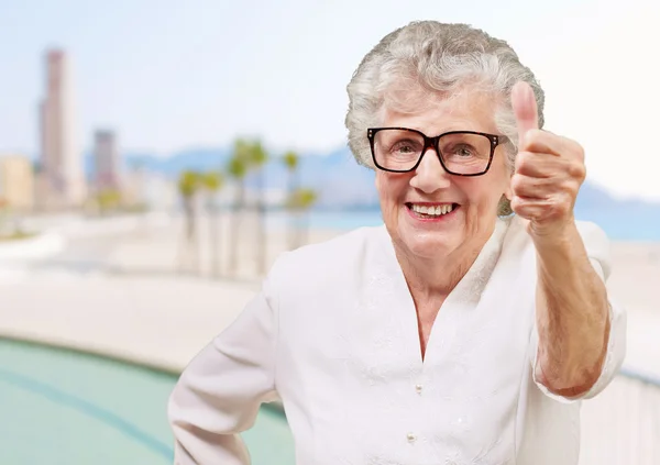 Портрет восхитительной пожилой женщины, делающей добрый жест рядом с домом — стоковое фото