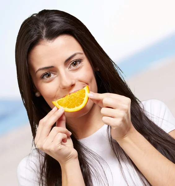 Портрет молодої жінки, що тримає апельсиновий шматочок на пляжі — стокове фото