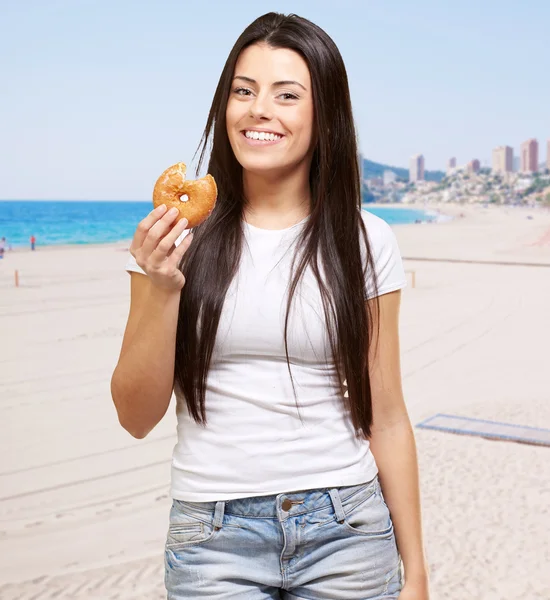 针对在海滩举行甜甜圈的年轻女人肖像 — 图库照片