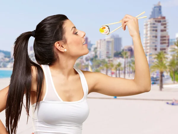 Mladá krásná žena jíst sushi na pláži — Stock fotografie