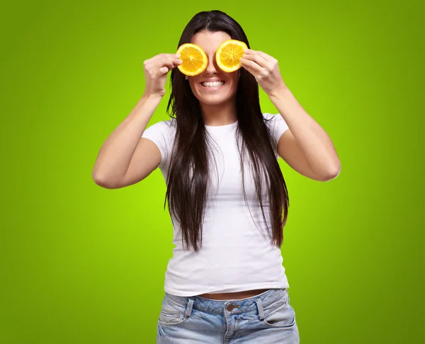 Portrait of young woman holding orange slices in front of her ey Stock Photo