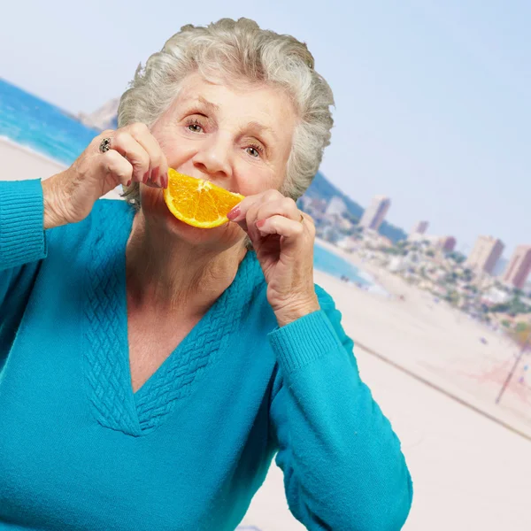 Portrait de femme âgée souriant et tenant une tranche d'orange en t — Photo