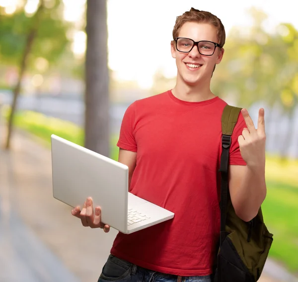 Retrato de jovem estudante segurando laptop no parque — Fotografia de Stock
