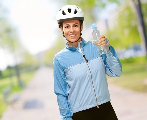 Retrato de ciclista mujer de mediana edad sosteniendo una botella de agua en —  Fotos de Stock